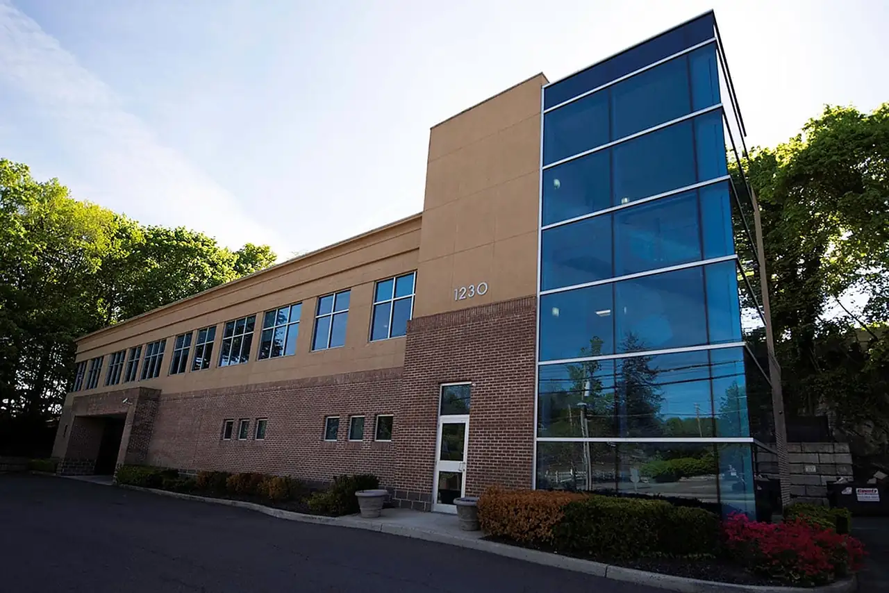 The practice's building at 1230 Mamaroneck Avenue, White Plains, brick and stucco beside a glass stair tower.